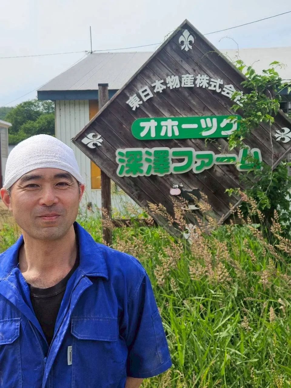 オホーツク深澤ファームの看板前に立つスタッフ