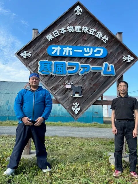 オホーツク寒風ファームの看板前に立つスタッフ